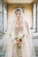 Bride in a wedding dress and a veil with a bouquet on an old terrace with columns. Lake Como