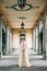 Bride in a wedding dress and a veil with a bouquet walks along the old terrace with columns. Lake Como
