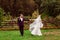 Bride whirls her veil while walking with groom in wine suit