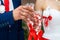 Bride in white dress and groom in dark blue suit clink glasses with beautiful handmade glasses at the wedding table