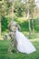 Bride In white dress and groom in military uniform kiss and embrace during walking in forest