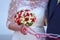 Bride in white dress holding a wedding colorful rose bouquet in her hand