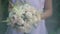 Bride in white dress holds in her hands beautiful delicate wedding bouquet