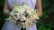Bride in white dress holds in her hands beautiful delicate wedding bouquet
