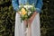 Bride in white dress and jean jacket with bouquet of flowers