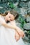 Bride in a white dress sits on stone steps with her head on her knees