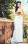 Bride in white dress standing on balcony in morning. Beautiful bride on terrace. Morning of bride