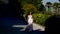 A bride in a white dress walks along the sunlit alley