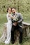 the bride in a white evening dress poses with the groom with a beautiful hairstyle, the groom gently wraps the bride and leans