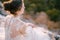 Bride in a white lace dress is sitting on the stones. Back view