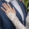 Bride in white lace dress wearing engagement ring and wedding ring. Happy newlyweds together