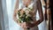 a bride in a white wedding dress, captured in a close-up image, with a delicate bouquet of flowers, standing by the