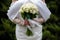 The bride in a white wedding dress is holding a bouquet of white flowers - peonies, roses. Wedding. Bride and groom. Delicate