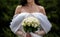 The bride in a white wedding dress is holding a bouquet of white flowers - peonies, roses. Wedding. Bride and groom. Delicate