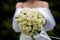 The bride in a white wedding dress is holding a bouquet of white flowers - peonies, roses. Wedding. Bride and groom. Delicate