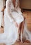 Bride in white wedding dress opened barefoot while sitting on a chair