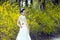 A bride with white wedding dress stand by Golden jasmine flowers