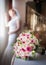 Bride in window frame and wedding bouquet in the foreground. Wedding bouquet with a woman in wedding dress in the background