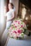 Bride in window frame and wedding bouquet in the foreground. Wedding bouquet with a woman in wedding dress in the background