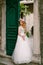 A bride with a wreath of roses stands at the green door in the cozy courtyard of the old town of Kotor