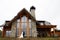 Brides morning. A woman in a wedding dress and a man in a stylish suit stand in front of a gorgeous house in the mountains