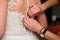 Bridesmaid hands fastens buttons on the back of the bride