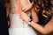 Bridesmaid hands fastens buttons on the back of the bride on the wedding white dress with corset