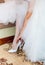 Bridesmaid helping bride to put on elegant shoes