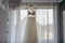 Bridesmaid helping slender bride lacing her wedding white dress, buttoning on delicate lace pattern with fluffy skirt on waist.