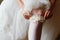 Bridesmaid helping slender bride lacing her wedding white dress, buttoning on delicate lace pattern with fluffy skirt on waist.