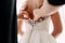 Bridesmaid helps fasten a wedding dress the bride before the ceremony. Wedding concept