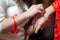 Bridesmaid helps to put a bracelet on his arm for the bride. bride putting on jewelry, focus on bracelet. Close up of groom giving