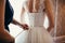 Bridesmaid makes bow-knot on the back of brides