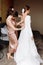 Bridesmaid& x27;s hands helping bride fastens with buttons on the back of a beautiful white wedding lace vintage dress close