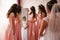 Bridesmaid standing by the mirror and help bride look at yourself. Big mirror at home. Happy girl`s in same dress