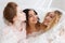 Bridesmaids and beautiful bride covered by veil standing in loft room interior. Close-up portrait