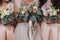 Bridesmaids and bride holding modern wedding bouquets of pink roses and green eucalyptus with pink ribbons. Stylish Contemporary