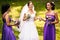 Bridesmaids help bride to put on earrings and necklace