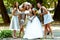 Bridesmaids lean to the bride while they pose in the park