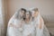 The bridesmaids look at the smiling bride. All on the same couch under a veil.