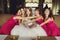 Bridesmaids in pink dresses hug a bride sitting on the sofa