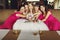 Bridesmaids in pink dresses lean to a pretty bride sitting on th