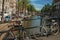 Bridge on canal with bicycle stuck at balustrade and moored boats in Amsterdam.