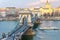 Bridge chain pendant sculpture lion through the Danube view of the shore of the Pest basilica of the holy Istvan in bright sunligh