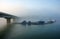 Bridge, fishing hamlet on lake in fog