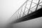 Bridge in the fog on misty winter day in black and white