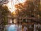 Bridge over a dark small lake with a red mill shining in the eve