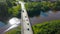 Bridge over the river from a drone . Clip. A bridge with cars and buses over the river and green fields behind which you