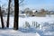 A bridge over a small creek, winter in the village, the ground under the snow.