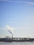 Bridge, pier, and steam chimney by ocean in winter